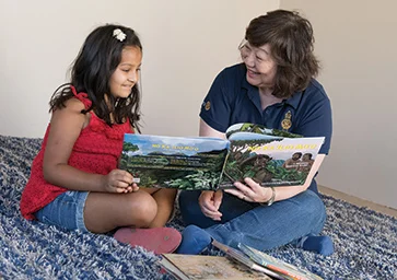 A Rotary member reading a book with a child.
